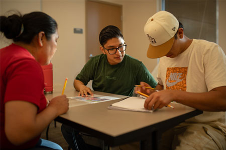 A Group of Three Students Reviewing English Language Learner Work Together