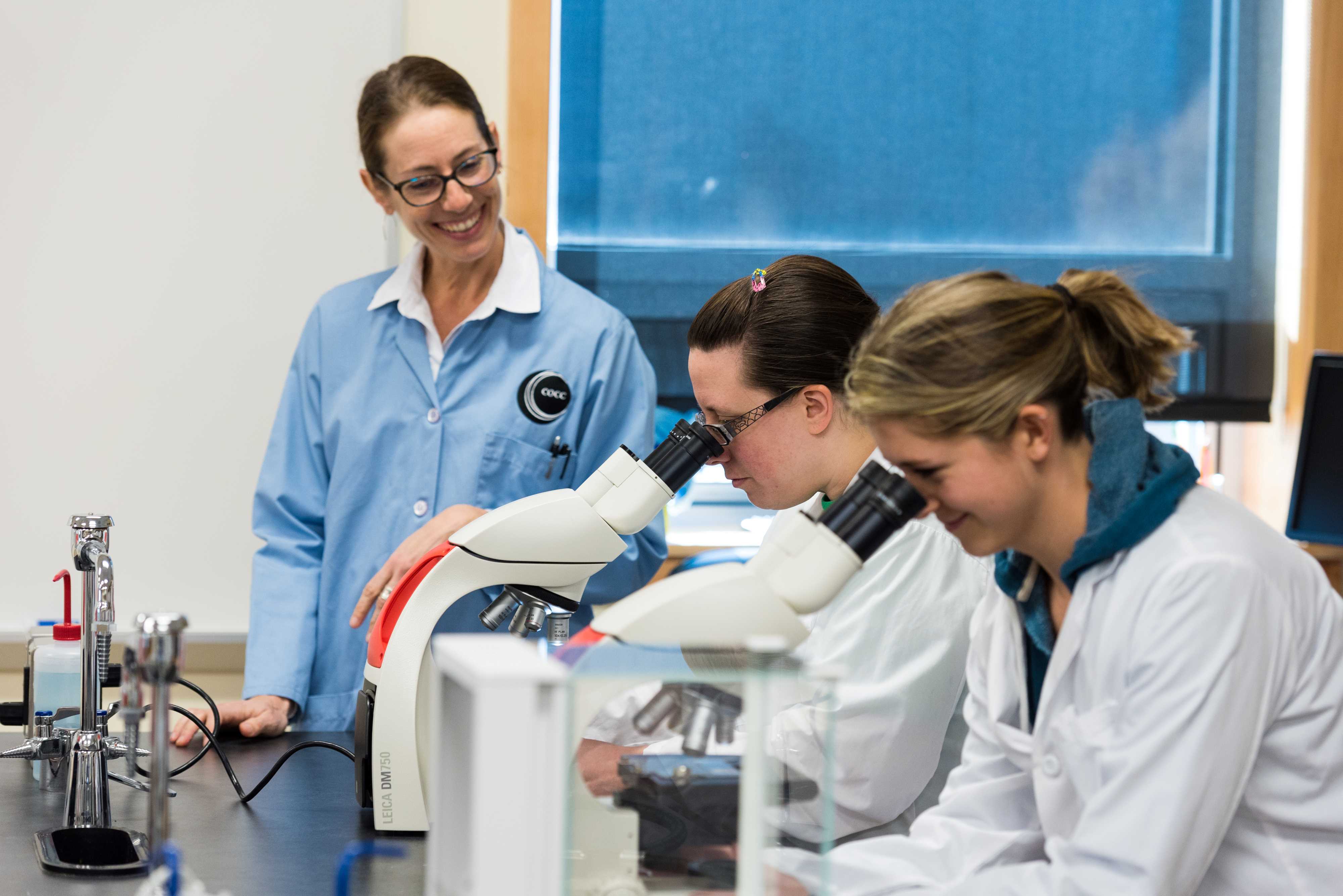 Teacher and students using microscopes