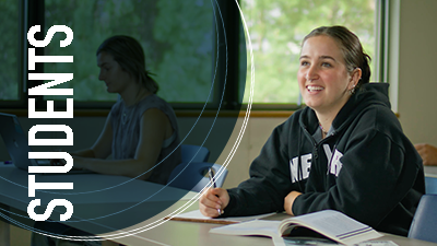 A young woman sitting at a desk looks up - presumably at her instructor - with a slight smile. the overlay reads: 'students'