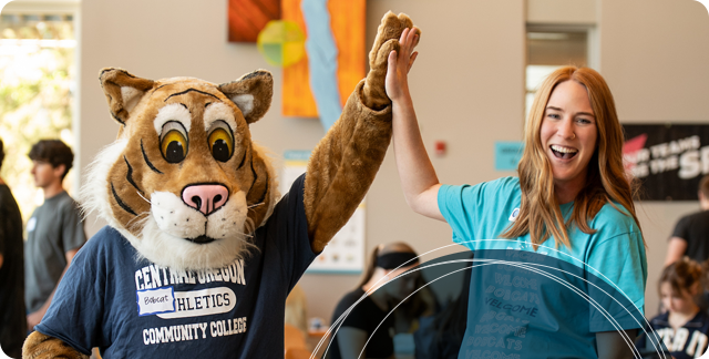 COCC Bobcat high fiving a staff member during orientation