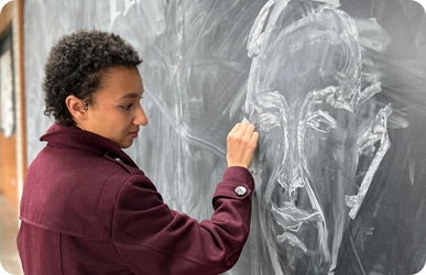 Student drawing a portrait on a chalkboard