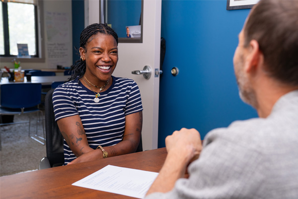A smiling student talks with an adviser during a one-on-one meeting