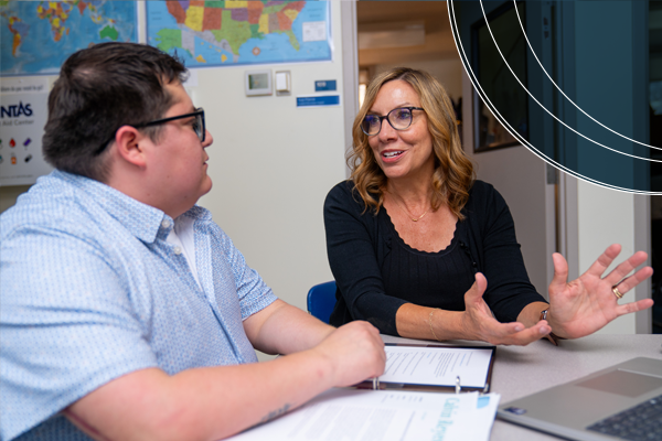 An adviser gestures while explaining options to a student during an advising session