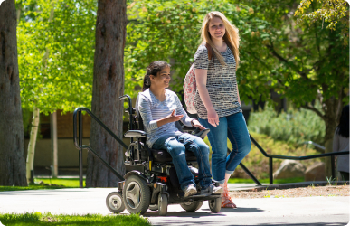 Smiling woman in wheelchair talks with standing woman