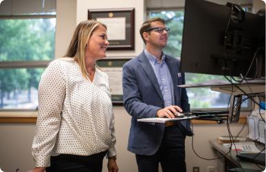 Two professionals discussing accessibility resources at a computer