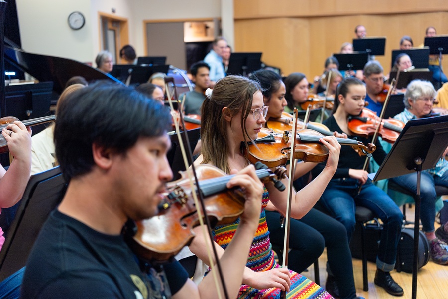male and female symphony musicians practicing, with violinists in foreground
