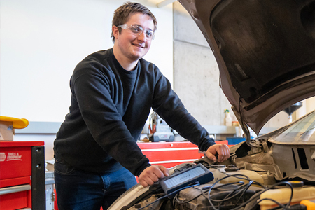 Automotive maintanence student working under car hood