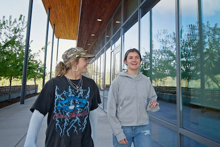 Two female friends walking together in front of Middleton Science Center.