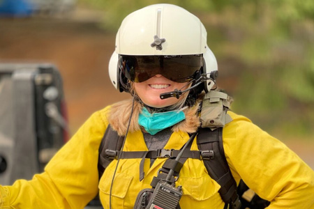 Woman with pilot helmet, visor, and firefighting uniform