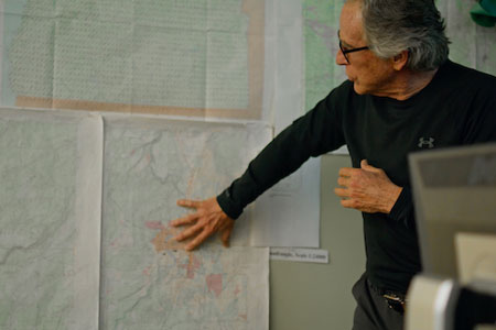Man in GIS environment analyzing maps on wall
